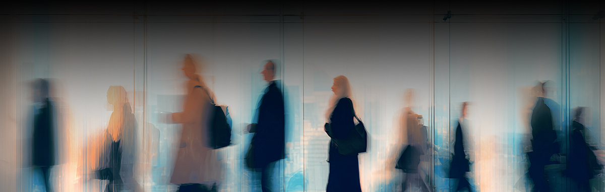 Blurry figures stride in a modern office space.