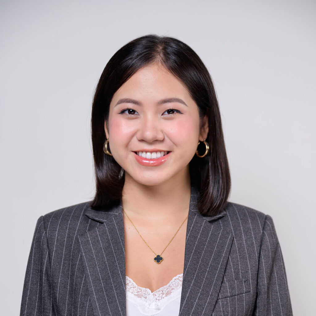 Headshot of a woman with straight black hair wearing a blazer smiling