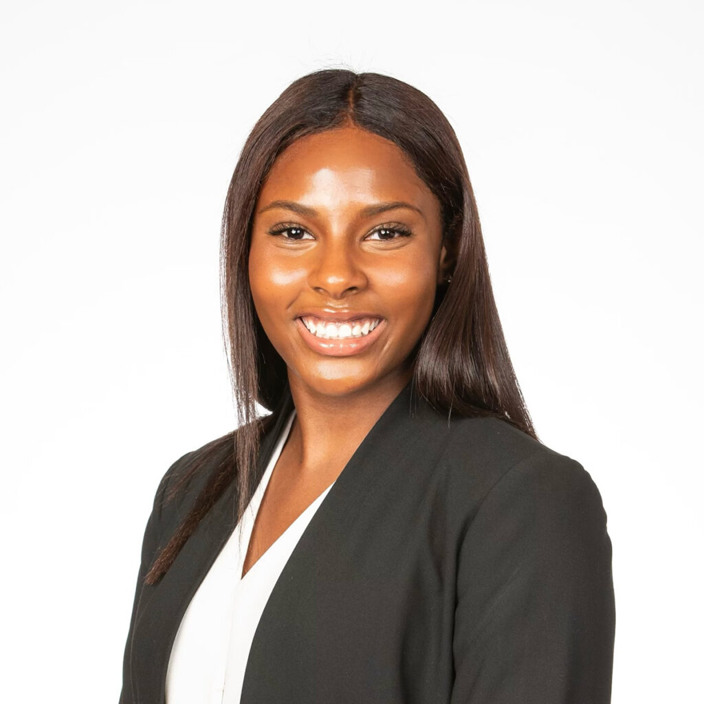 Headshot of a woman with dark hair wearing a black blazer and white shirt smiling at the camera