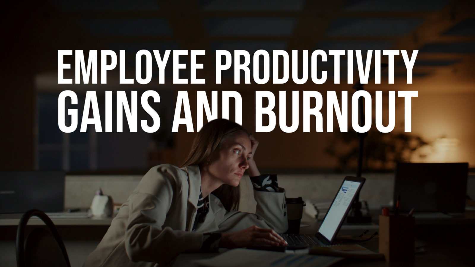 Promotional graphic showing a person seated at a desk at night, leaning toward a laptop in a dimly lit office. Large white headline text reads: “EMPLOYEE PRODUCTIVITY GAINS AND BURNOUT.”